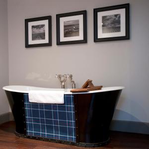 a bath tub in a bathroom with pictures on the wall at Hotel Du Vin Edinburgh in Edinburgh