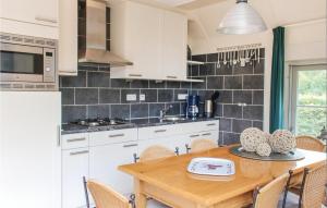cocina con armarios blancos y mesa de madera en Beautiful Home In Den Ham With Wifi, en Den Ham