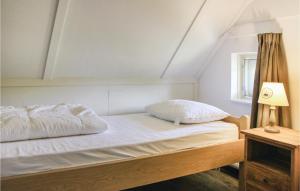 uma cama com lençóis brancos e almofadas num quarto em Pet Friendly Home In Den Ham With Wifi em Den Ham