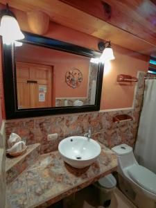 a bathroom with a sink and a toilet and a mirror at Hotel Utz Jay in Panajachel