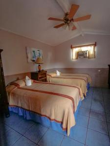 2 Betten in einem Hotelzimmer mit Deckenventilator in der Unterkunft Hotel Utz Jay in Panajachel