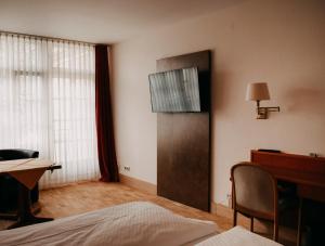 a room with a bed and a desk and a television at Badischer Hof in Tauberbischofsheim