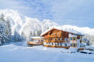 a log cabin in the snow with mountains in the background at Landhaus Kristall in Leutasch