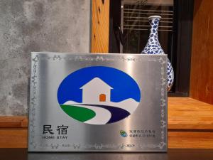 un panneau avec une maison à côté d'un vase dans l'établissement 似禾苑民宿 Siheyuan Homestay, à Sanxing