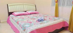 a bed with a pink and white blanket and shoes on it at Cahaya Kasih Homestay in Kangar
