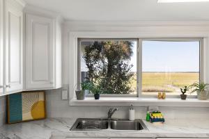 a white kitchen with a sink and a window at 1684 E Ashley - Sol Searcher - 2 Bedrooms in Folly Beach