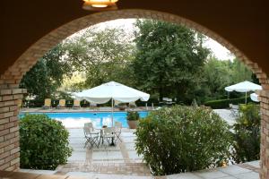 an archway leading into a pool with tables and umbrellas at Hotel Antonios in Olympia