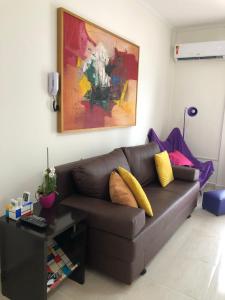 sala de estar con sofá marrón con almohadas amarillas en Apto. frente ao mar no Gonzaga - melhor localização! en Santos
