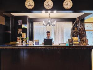 a man sitting at a counter with a laptop at The Camelot Beach Resort - Baga in Baga