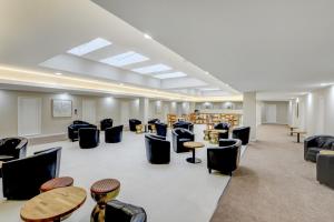 uma sala de espera com cadeiras, mesas e livros em OYO Plymouth Central Hotel em Plymouth