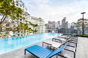 a pool on the roof of a building with benches at The Quarter Ploenchit by UHG in Bangkok