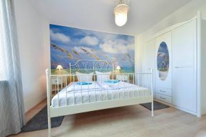 ein Schlafzimmer mit einem weißen Bett und einem Wandbild in der Unterkunft Haus Thalia 3 - Seestern in Ahlbeck