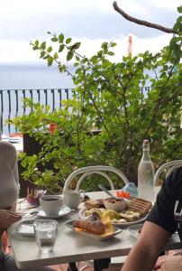 a person sitting at a table with food and drinks at B&B La Terrazza Sul Mare Taormina in Taormina