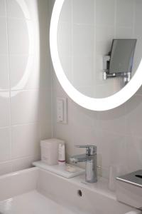 a bathroom with a sink, mirror and toilet at Relais De La Malmaison Paris Rueil Hôtel-Spa in Rueil-Malmaison