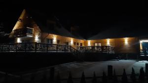 uma casa de madeira à noite com luzes acesas em Agroturystyka SABAT em Imielno