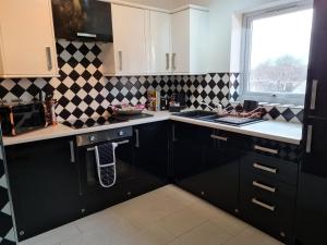 uma cozinha com armários pretos e uma parede xadrez em Stockton Heights, Warrington, Centrally Located Between Town Centre and Stockton Heath, High Speed Wifi, Cozy Stay em Warrington