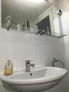 ein Waschbecken mit einem Spiegel und einer Flasche Seife in der Unterkunft "IDEAL" - für Zwei in Berlin