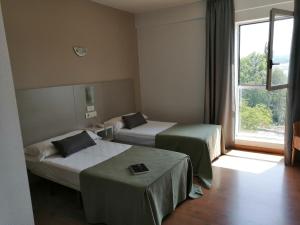 a hotel room with two beds and a window at Duerming Villa De Sarria Hotel in Sarria