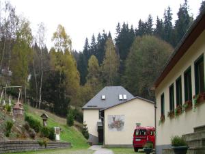 ein roter Van vor einem Gebäude geparkt in der Unterkunft Pension Waldidyll in Stützerbach