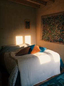 um quarto com uma cama branca e uma pintura na parede em Gîte au haras des arts em Saint-Aubin-de-Bonneval