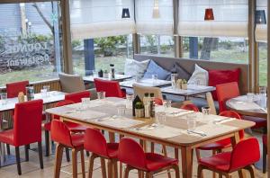 un comedor con mesas y sillas rojas en Campanile Argenteuil, en Argenteuil