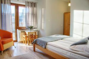 a bedroom with a bed and a chair and a table at DW Pod Jaworami - relaks w SPA - jacuzzi, sauna na wyłączność in Białka Tatrzańska