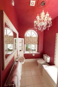 un bagno con pareti rosse e lampadario a braccio di Glewstone Court Country House Hotel a Ross on Wye