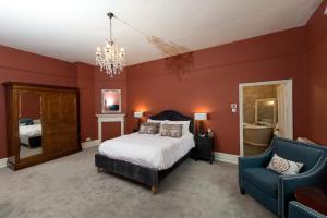 a bedroom with red walls and a bed and a chair at Glewstone Court Country House Hotel in Ross on Wye