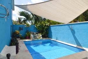 a swimming pool in a blue wall with a umbrella at Hotel Villas Las Anclas in Cozumel