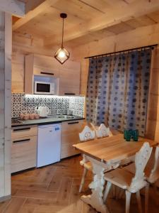 uma cozinha com uma mesa de madeira e electrodomésticos brancos em Górska Chata Pod wyciągami Remiaszów i Jankulakowski Skibus pod domkami em Białka Tatrzanska