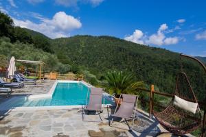 a swimming pool with chairs and a mountain at Agriturismo Casa Turchetti in Comano
