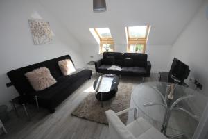 a living room with a black couch and a glass table at Holden Court Apartment 5 in West Drayton