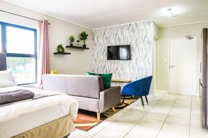 a bedroom with a bed and a couch and a chair at Insaka's Greenlee Apartment - Greenlee Lifestyle Centre, Sandton in Sandown