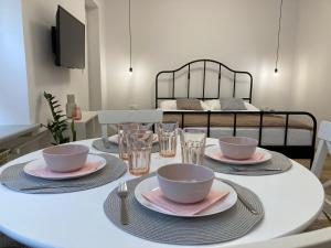 a white table with bowls and plates on it with a bed at Duo 1 Debniki Apartment in Krakow