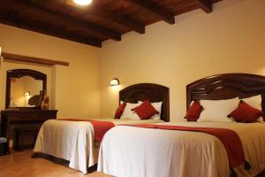 - une chambre avec 2 lits dotés d'oreillers blancs et rouges dans l'établissement Parador Margarita, à San Cristóbal de Las Casas