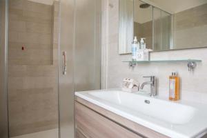 W łazience znajduje się umywalka, lustro i prysznic. w obiekcie Villa Olivee w mieście Bellagio