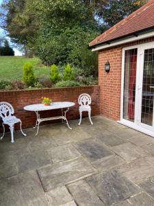 un patio con mesa, 2 sillas y una pared de ladrillo en The Garden Room en Ipswich