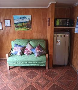 a green couch in a room with a refrigerator at Cabaña Patagonia Rustica in Coihaique