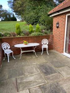un patio con mesa, 2 sillas y una pared de ladrillo en The Garden Room, en Ipswich