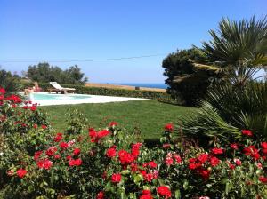 un jardín con flores rojas y una piscina en Appartamento sulla Riviera del Conero, en Numana