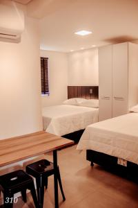 a room with two beds and a wooden table at Loft próximo a Vila Germânica 310 in Blumenau