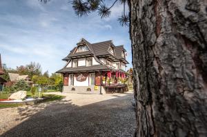 dom z czarnym dachem z czerwonymi flagami w obiekcie GÓRALSKA VILLA APARTAMENTY Z JACUZZI & HOME SPA & Zakopane w Poroninie