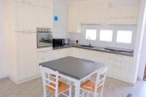 a kitchen with white cabinets and a table and chairs at Villetta Cinzia Vista Mare in Villaputzu
