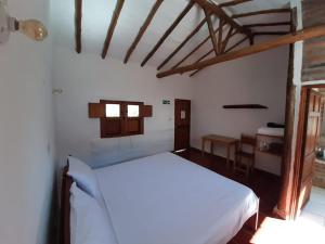 ein Schlafzimmer mit einem weißen Bett und einem Tisch in der Unterkunft Artepolis in Barichara