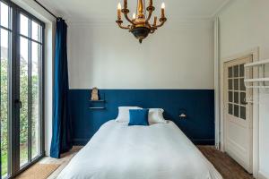 a bedroom with a large bed with blue walls and a chandelier at The westhouse in Middelkerke