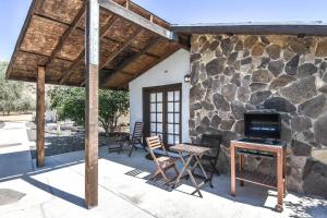 een patio met een stenen muur en een tafel en stoelen bij Quinta Monasterio in Valle de Guadalupe