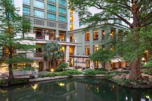 a hotel with a pond in front of a building at Hotel Contessa - Suites on the Riverwalk in San Antonio