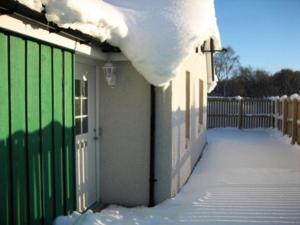 ein Haus mit grünem Tor im Schnee in der Unterkunft Tieveragh in Aviemore