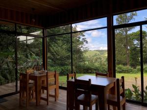 a dining room with a table and chairs and large windows at Tityra Lodge in Monteverde Costa Rica