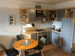 uma cozinha com uma mesa e cadeiras de madeira, uma mesa e um frigorífico em Nordlicht in Büsum-Stinteck em Stinteck
